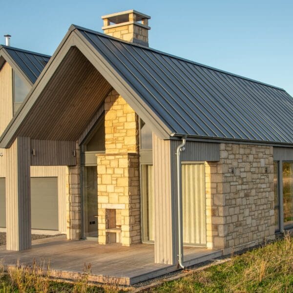 Exterior of modern build house with grey pitched roof and light sandstone cladding