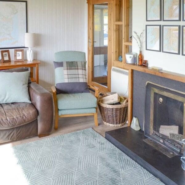 Living room with brown leather couch and black slate fireplace. Wester Lonemore, Dornoch