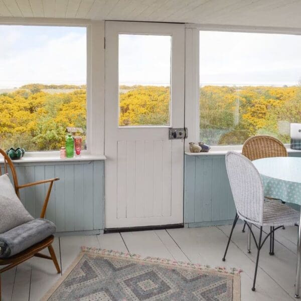 Sunlounge interior with pale blue decor and view to yellow gorse, Wester Lonemore, Dornoch