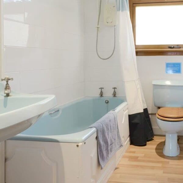 Bathroom with pale blue suite and shower above bath, Wester Lonemore, Dornoch
