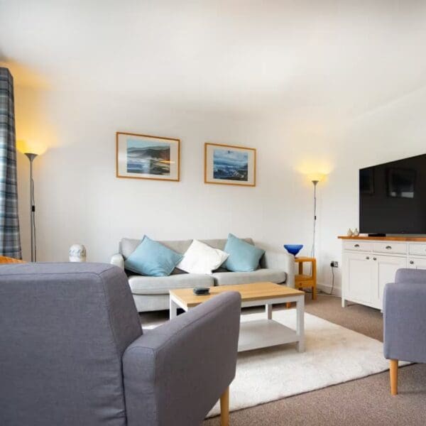 Lounge in Thistledown, Dornoch with purple and grey furnishings, black tv and tartan curtains