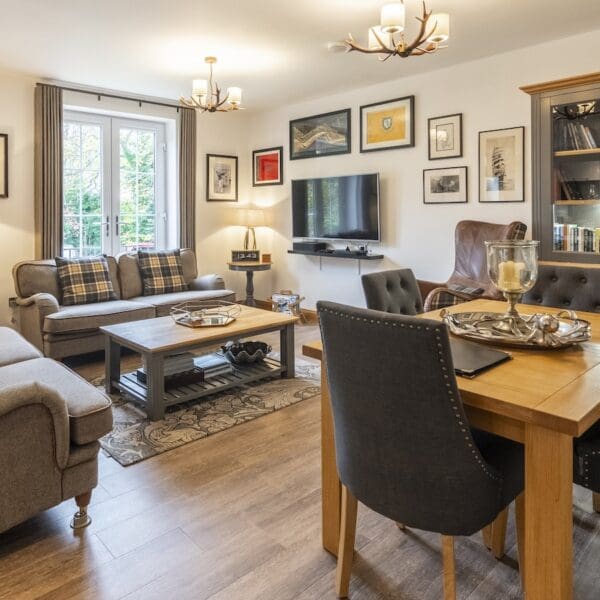 Living and dining area with dark grey couches and seats with pine dining table, 13 Royal Golf Apartments Dornoch