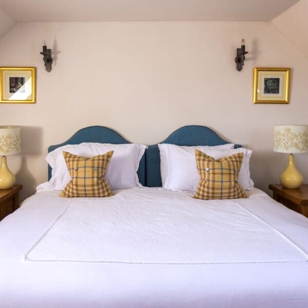 Double bedroom with blue headboards, yellow tartan cushions and table lamps in Balvraid Steading, near Dornoch