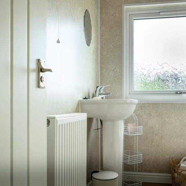 View into bathroom with white sink and light cream walls
