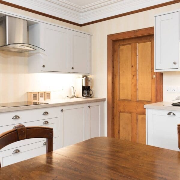 Kitchen with white cabinets and dark wood table and chairs in Balloan House, Dornoch