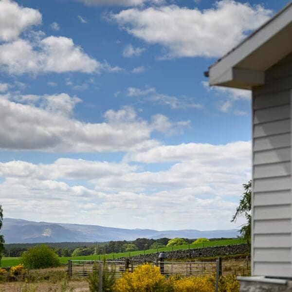 View across countryside with corner of wooden clad chalet building in foreground