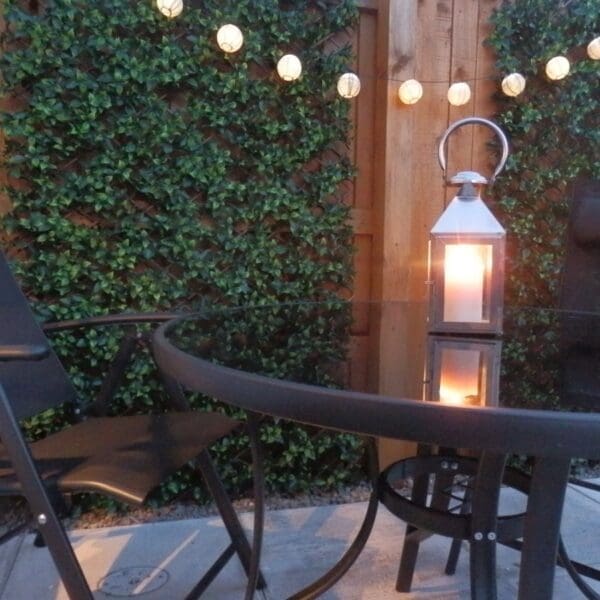 Outside seating area with black garden table and chairs, lanturn lights and greenery up wooden fence, Glen Brodie self catering, Dornoch