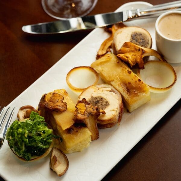 oblong white plate with autumnal meat and vegetable dish, set on dark wood table