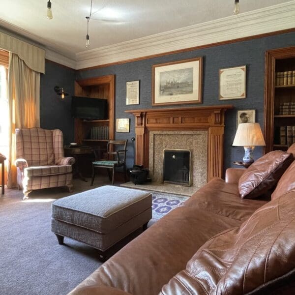 Living room with large brown leather sofa, blue feature wall and fireplace