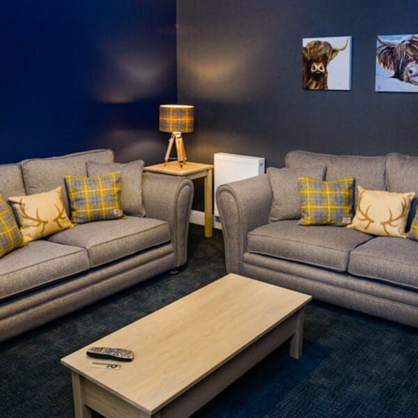 Living room with grey couches and dark blue painted walls in Burnside Cottage, Dornoch