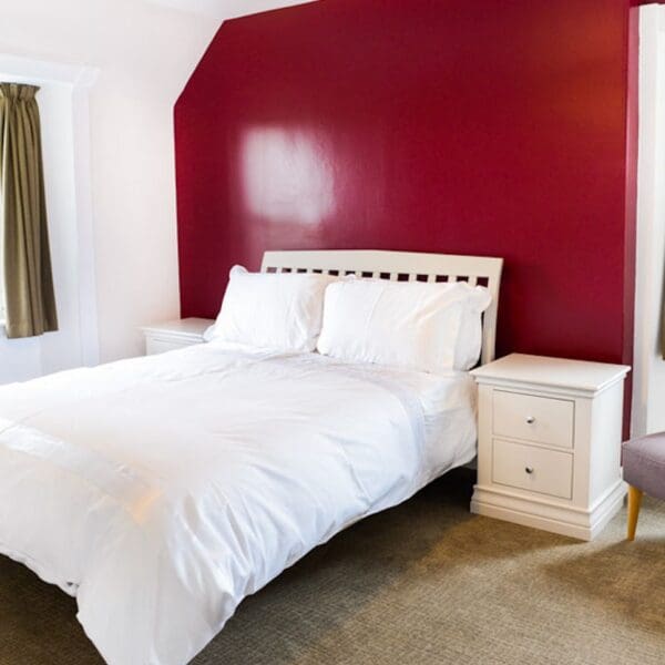 Bedroom with double bed and red feature wall in Burnside Cottage, Dornoch