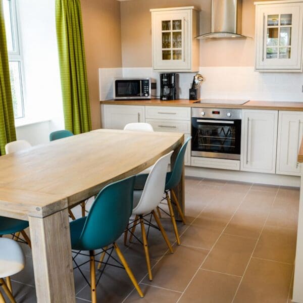 Kitchen with cream cabinets and wooden dining table in Burnside Cottage, Dornoch