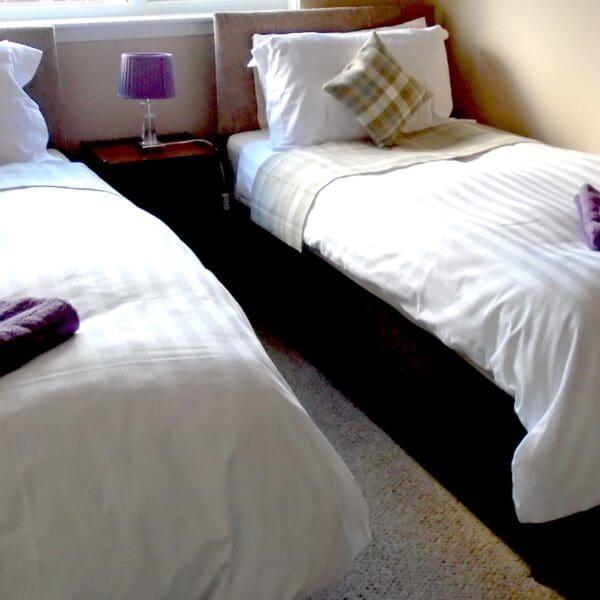 Twin bedroom with white bedspreads and tartan cushions, Oystercatcher holiday cottage, Embo