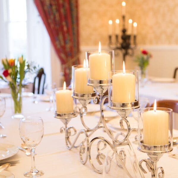 close up of dining room table set with white cloth, silver candelabra in yellow walled dining room