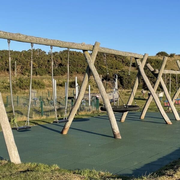Children's play equipment in play park area set in sand dunes at beach with blue skies on sunny day