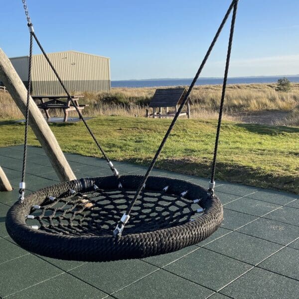 Children's play equipment in play park area set in sand dunes at beach with blue skies on sunny day
