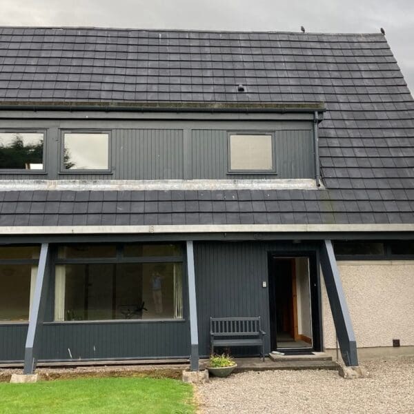 Exterior frontage of A Frame building with grey cladding and roof tiles, West Dune apartment, Dornoch