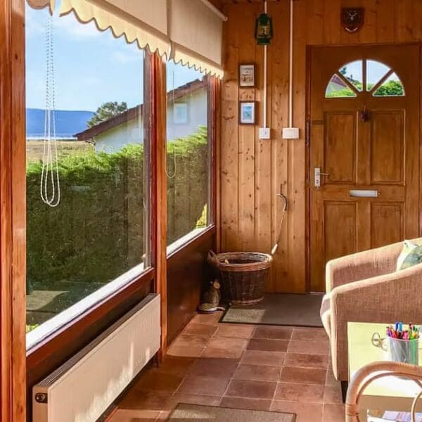 Sun lounge in Achnacarry, Dornoch with pine lined walls, bucket chair and yellow coffee table