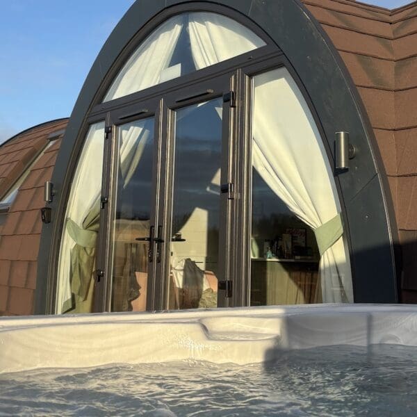 Exterior of wooden camping pod accommodation unit with hot tub in foreground