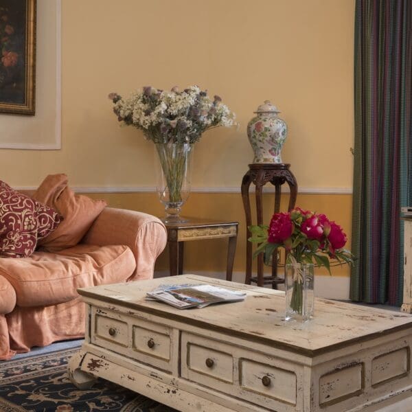 living room with yellow walls, peach couch and cream painted coffee table