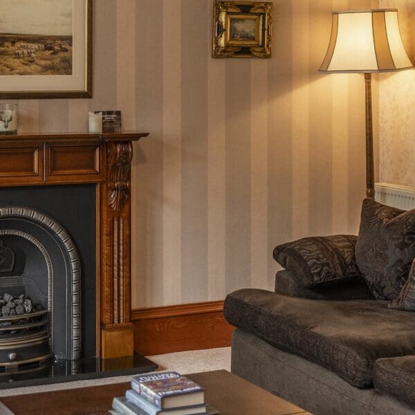 Living room detail with pitch pine fireplace mantlepiece, iron fireplace, brown couch and dark wood coffee table