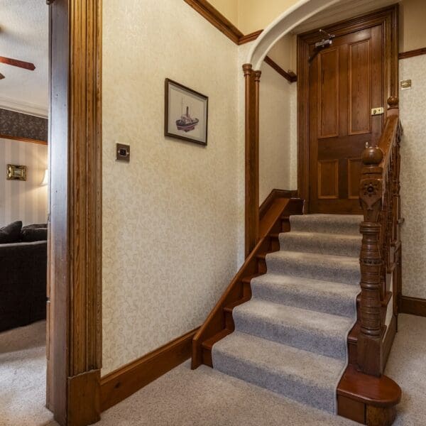 Hallway with cream walls, pitch pine bannister and detailing and light grey carpet