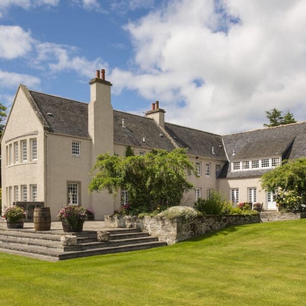 Exterior of Glenmorangie House Hotel, cream render on large stone house with grass lawn
