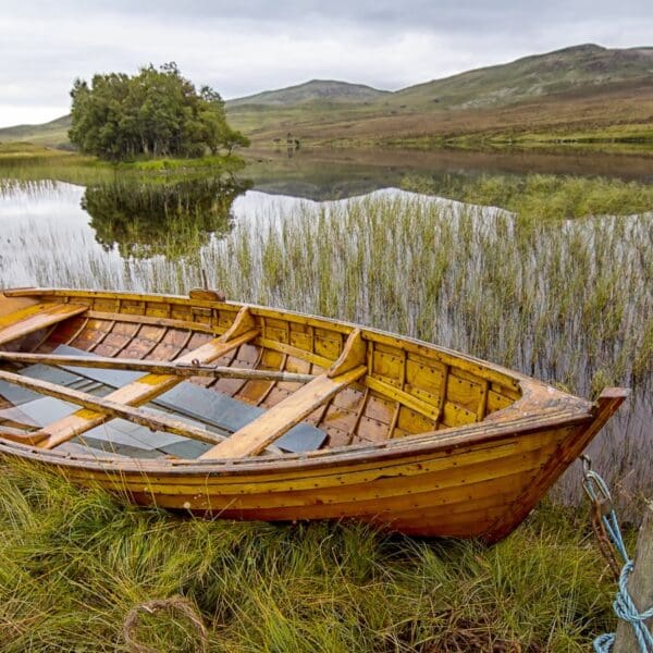 Wooden rowing boat pulled onto bank of Scottish loch