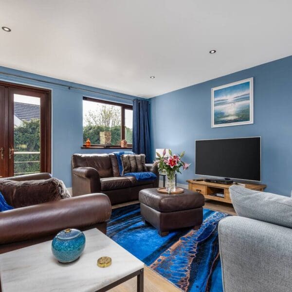 Living room with blue walls and brown leather suite, Orcadia self catering house, Dornoch