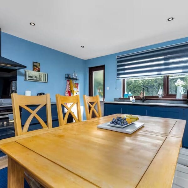 Kitchen with blue walls, dark blue units and pine dining table, Orcadia self catering house, Dornoch