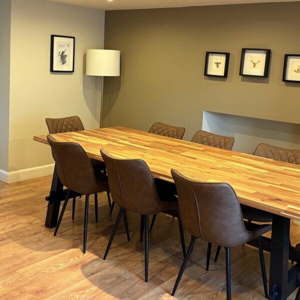 Dining room with wooden table, chairs with brown leather seats and olive green painted walls