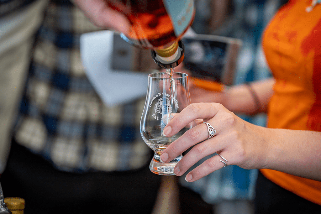 Whisky being poured into a glass saying Dornoch Whisky Festival.