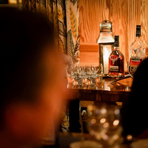 Side table against wooden wall with bottles of Dalmore Whisky