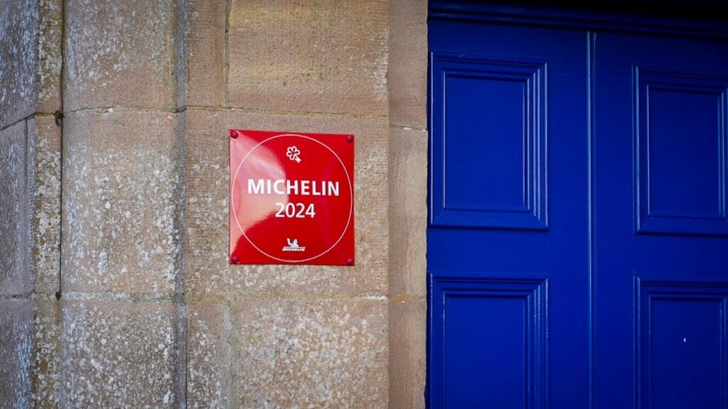 Red Michelin sign on stone wall next to blue door, Links House Dornoch 1660 x 900