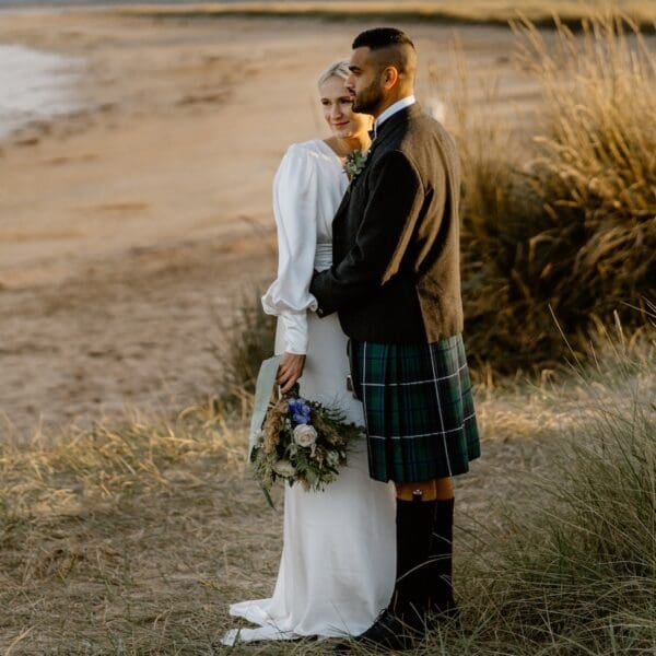 Bride and Groom standing on dunes overlooking Dornoch Beach, credit Marine & Lawn hotels and Steven Gallagher Photography