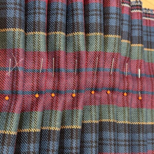Pleated tartan with orange-tipped pins holding in place
