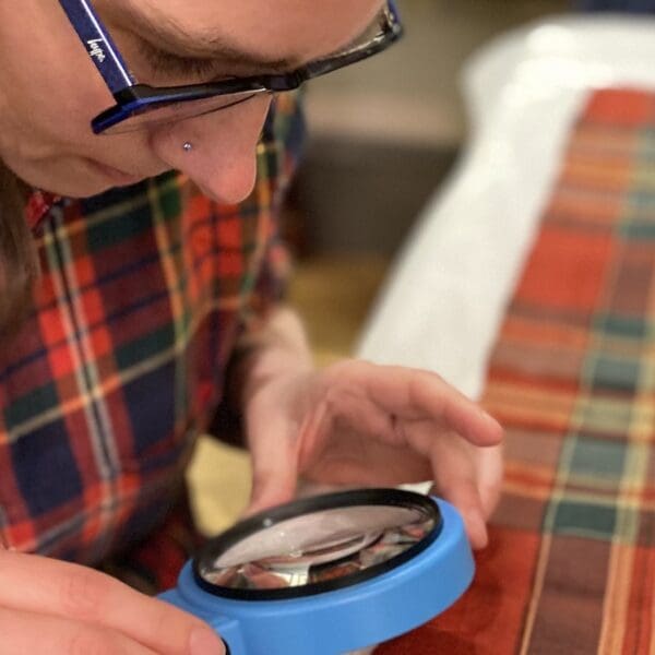 Female looking at bolt of tartan through magnifying glass
