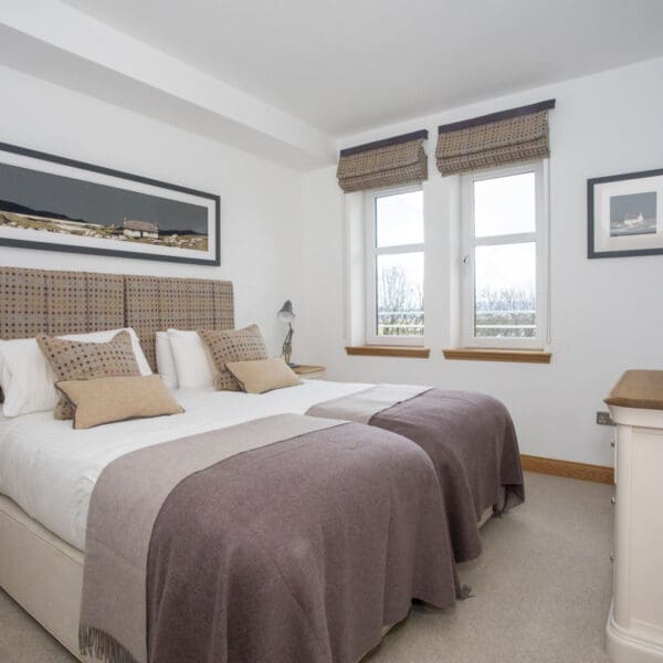 White bedroom with twin beds, white sheets and purple blankets
