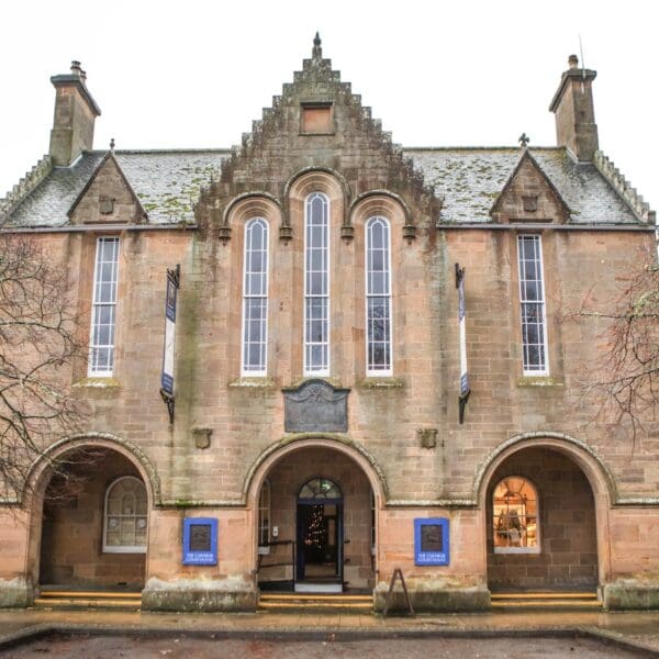 Exterior of Carnegie Courthouse building in Dornoch, stone court building with three archways at ground floor level and long slender windows on upper floor
