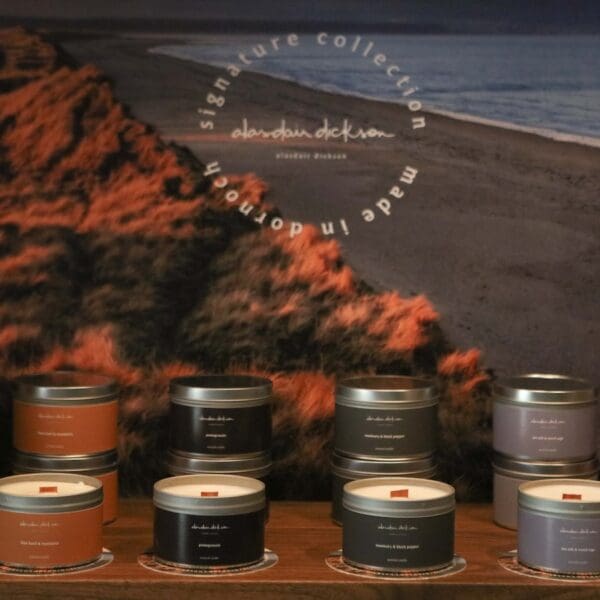 Alasdair Dickson candles displayed in front of image of beach