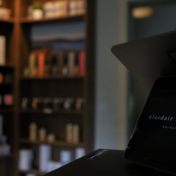 Alasdair Dickson candles displayed on shelves in shop with retail til in foreground