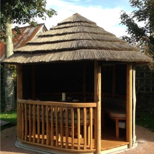 Covered garden seating area with thatched roof and wooden railing