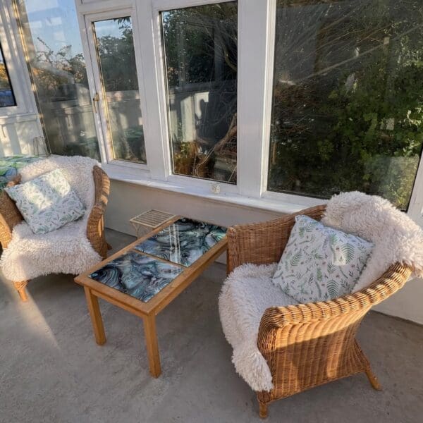 Sunlounge with two wicker seats with cream throw blankets and a coffee table
