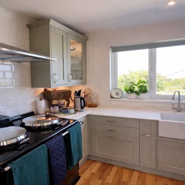 Kitchen with dark green Aga range, light green cabinets and white counter top
