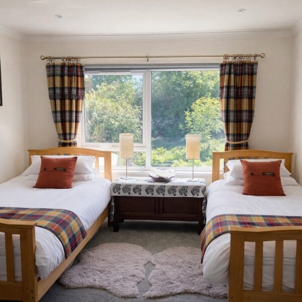 Twin bedroom, white walls, tartan curtains and blanket throws on beds, grey carpet