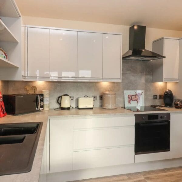 Kitchen with gloss white cabinets, cream walls and black sink
