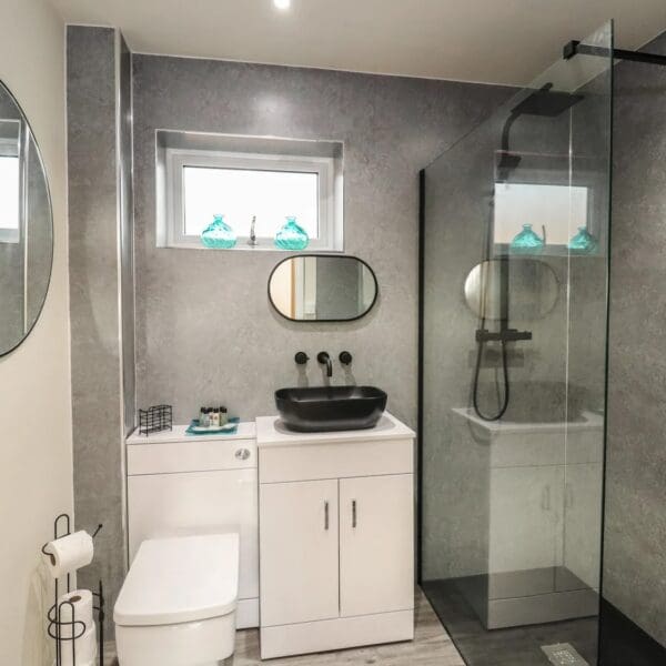 Bathroom with light grey wetwall and white toilet and sink unit