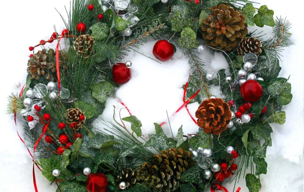 a photo of a green Christmas wreath with red baubles, cones and silver and red balls.